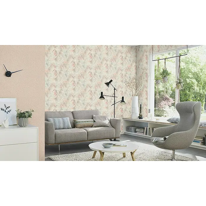 Rasch Tapetenwechsel 2 Vliestapete Vintage - Terra, Grafisch, 10,05 x 0,53 m - Ein stilvolles Wohnzimmer mit einer gemusterten Tapete, einem grauen Sofa und einem modernen Sessel, das ein gemütliches Ambiente schafft.