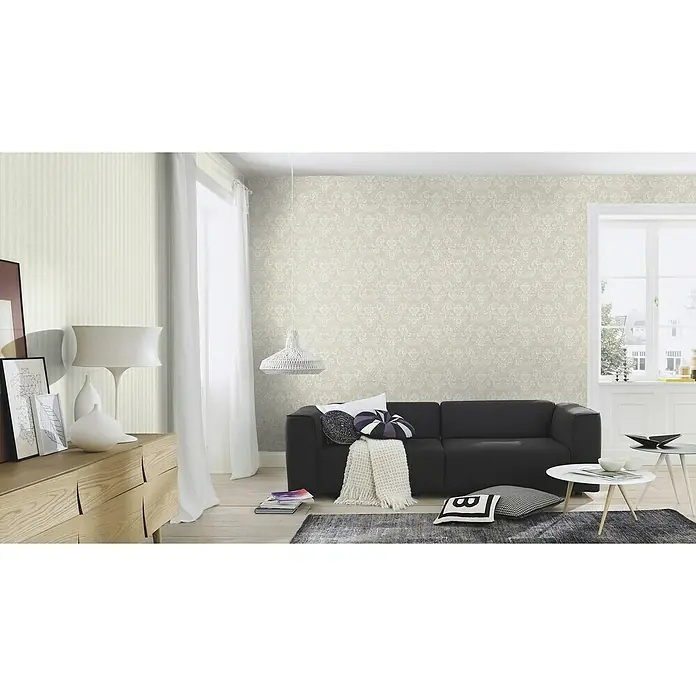 Rasch Trianon XIII Vliestapete - Weiß, Streifen, 10,05 x 0,53 m - Ein stilvolles Wohnzimmer mit einer modernen schwarzen Couch, gemusterten Kissen und einer eleganten Lampe. Die Tapete verleiht dem Raum eine edle Note.