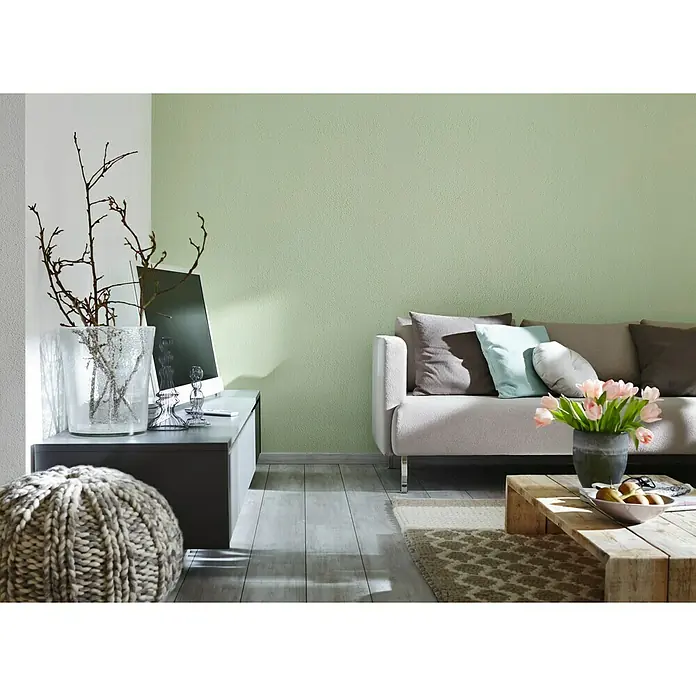 Knauf Putz-Abtönfarbe Compact Color - Jade, 2 g - Wohnzimmer mit Sofa, Couchtisch, Kommode und Deko. Die Wand ist hellgrün gestrichen, was eine freundliche Atmosphäre schafft.