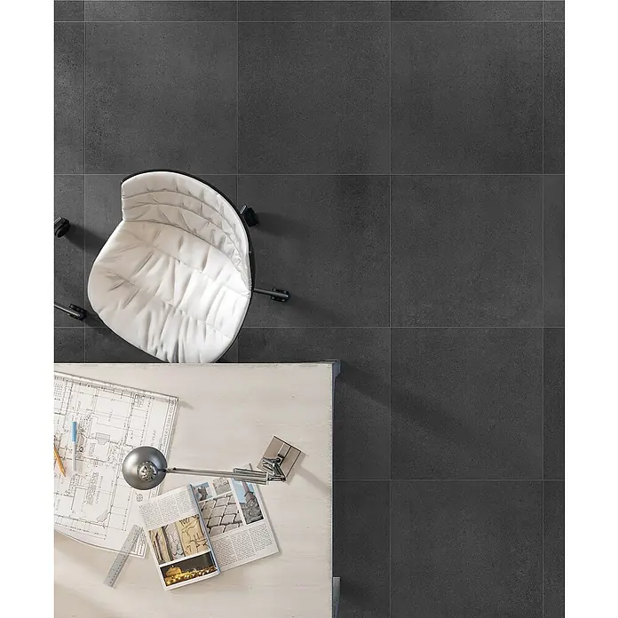 Art-Tec by Palazzo Feinsteinzeugfliese - 80 x 80 cm, Graphit, Schimmernd - Dunkelgraue Bodenfliesen mit einem Bürostuhl und einem Schreibtisch mit Zeitschriften und Bauplänen für ein modernes Bürodesign.