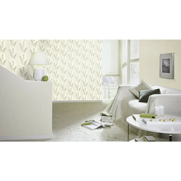 Rasch Tapetenwechsel 2 Vliestapete Blätter - Hellbeige, Floral, 10,05 x 0,53 m - Ein helles Wohnzimmer mit floral gemusterter Tapete, einer weißen Couch und einem runden Tisch. Die Tapete verleiht dem Raum eine gemütliche Atmosphäre.