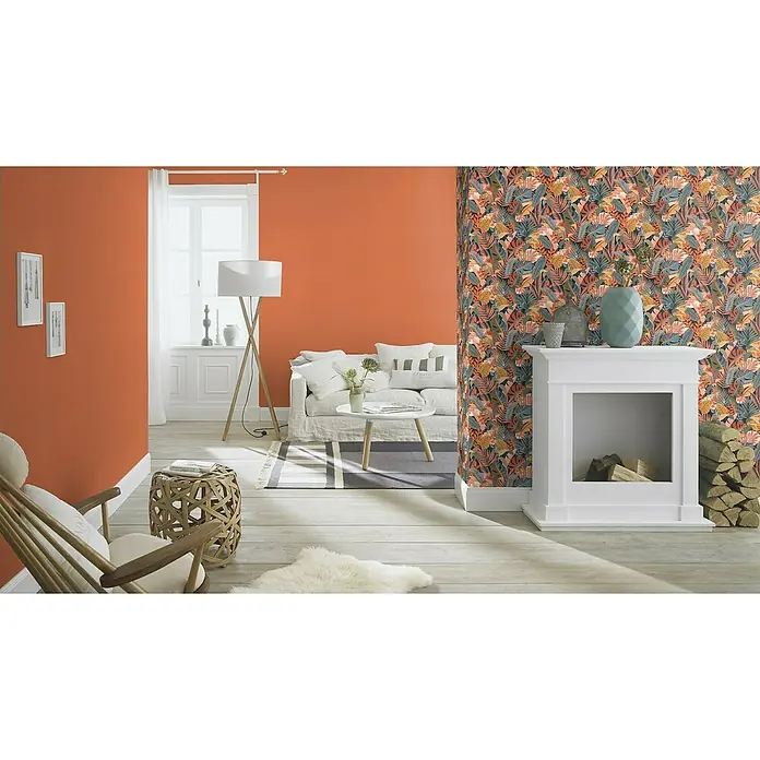 Rasch Tropical House Vliestapete - Dunkelorange, Uni, 10,05 x 0,53 m - Helle Wohnungseinrichtung mit orangefarbener Wand, floraler Tapete, Sofa, Kamin und Holzboden für ein gemütliches Ambiente.