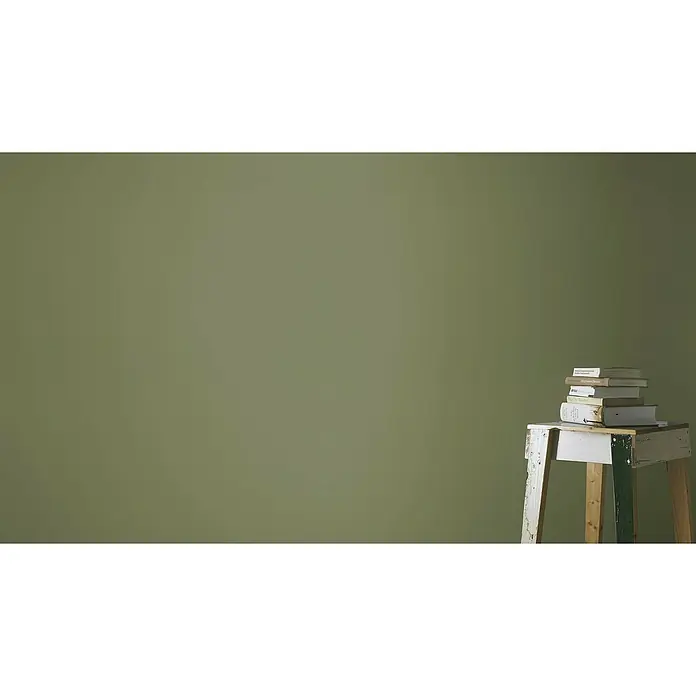 Rasch Tropical House Vliestapete - Moosgrün, Uni, 10,05 x 0,53 m - Eine Nahaufnahme von einem Stapel Büchern auf einem kleinen, rustikalen Hocker vor einem olivgrünen Hintergrund.