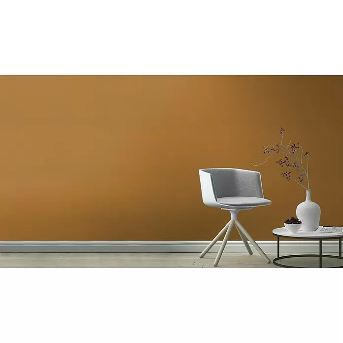Rasch Tropical House Vliestapete - Cognac, Uni, 10,05 x 0,53 m - Moderner weißer Stuhl mit grauem Stoffbezug und hellen Holzbeinen, neben Beistelltisch an orangefarbener Wand.