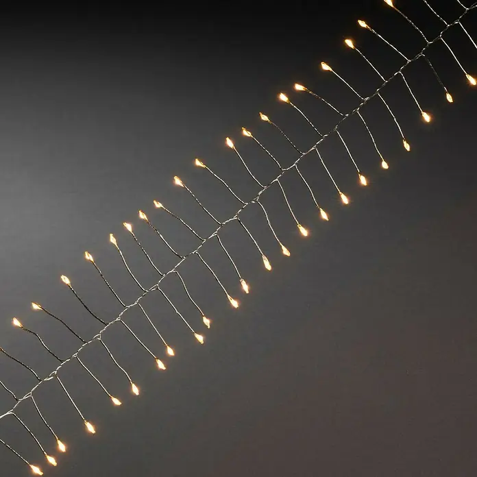 Konstsmide LED-Lichterkette Micro LED Firecracker - Innen, Lichtfarbe: Bernstein, Anzahl Leuchtmittel: 60 Stk., Batteriebetrieben, Silber - Nahaufnahme einer Lichterkette mit warmweiß leuchtenden LEDs, die ein festliches und gemütliches Ambiente erzeugen. Ideal für die Dekoration.
