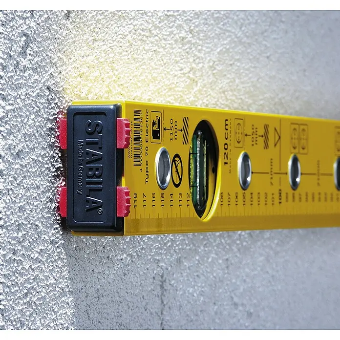 Stabila Wasserwaage Typ 70 electric - Länge: 43 cm, Anzahl Libellen: 2 Stk. - Nahaufnahme einer gelben Stabila Type 70 Electric Wasserwaage, die an einer Wand befestigt ist und die Genauigkeit bei Elektroinstallationen gewährleistet.