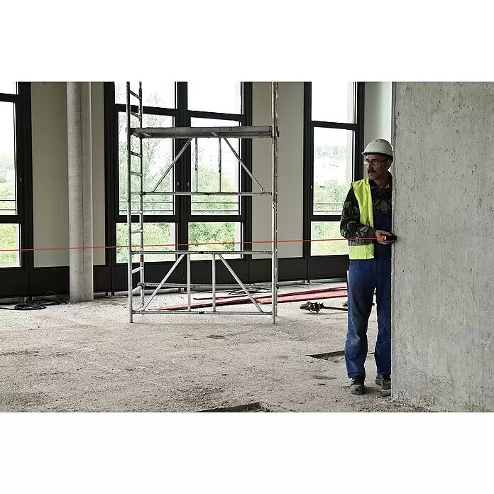 Stabila Laserentfernungsmesser LD 320 - Messbereich: 0,05 - 40 m - Bauarbeiter mit Schutzhelm und Warnweste misst auf einer Baustelle mit Gerüst und Laserlinie.
