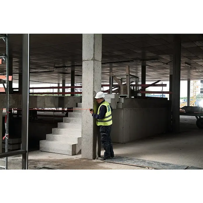 Stabila Laserentfernungsmesser LD 320 - Messbereich: 0,05 - 40 m - Baustellenarbeiter mit Schutzhelm und Warnweste misst eine Betonsäule mit einem Messwerkzeug. Der Innenraum ist im Bauzustand.