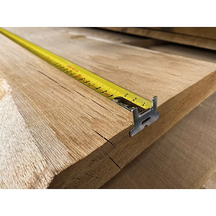 Stabila Taschenbandmaß BM 300 - 5 m - Nahaufnahme von einem gelben Rollbandmaß, das auf einem hellen Holzbrett liegt, welches die Länge des Bretts misst.