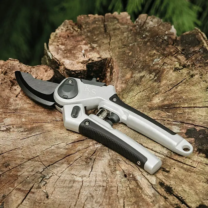 Kent & Stowe Gartenschere Eversharp Lite - Bypass - Gartenschere auf einem Baumstumpf. Die Schere ist silbern und schwarz mit einer scharfen Klinge zum Beschneiden von Pflanzen.