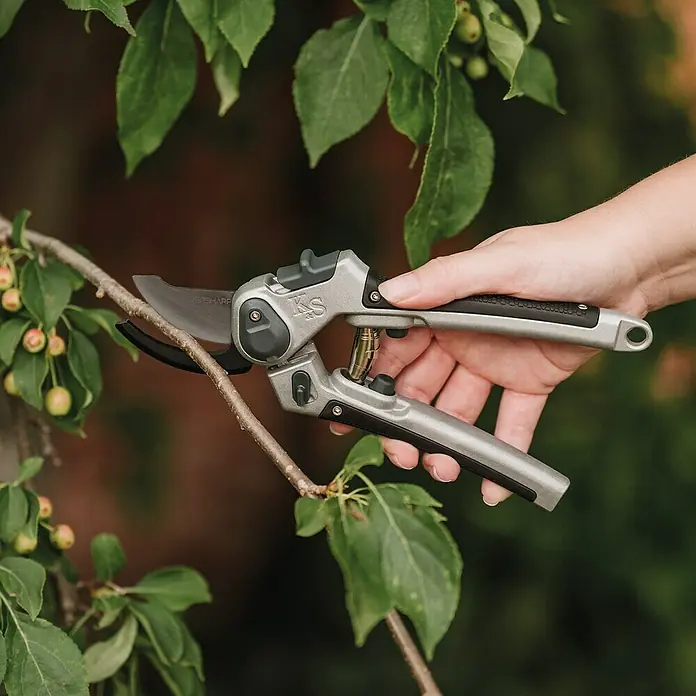 Kent & Stowe Gartenschere Eversharp - Bypass - Die Fiskars PowerGear Astschere wird von einer Hand gehalten, die einen Ast durchtrennt. Sie ist ein praktisches Werkzeug für die Gartenarbeit.