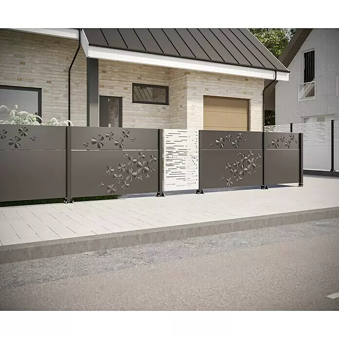Gabio Zaunelement Glücksklee - 197,5 x 45 cm, Stahl, Anthrazit - Dunkelgrauer Metallzaun mit Blumenausschnitten und weißes Tor mit horizontalen Ausschnitten vor einem Haus an einem Gehweg.