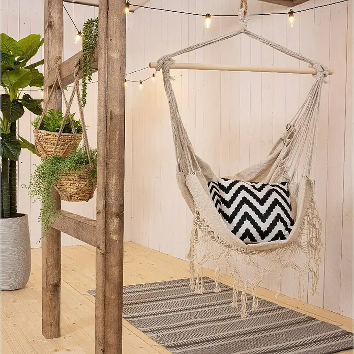 Hamaca colgante Bali - L x An x Al: 100 x 30 x 130 cm, Beige - Habitación colgante con una silla suspendida, una alfombra de rayas grises y plantas en cestas colgantes, creando un ambiente acogedor y relajante.