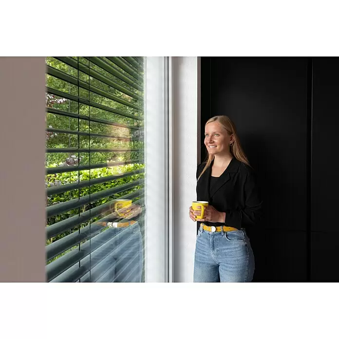 Schellenberg Raffstore Express - 140 x 260 cm - Gelbe Tasse, von einer blonden Frau am Fenster gehalten.