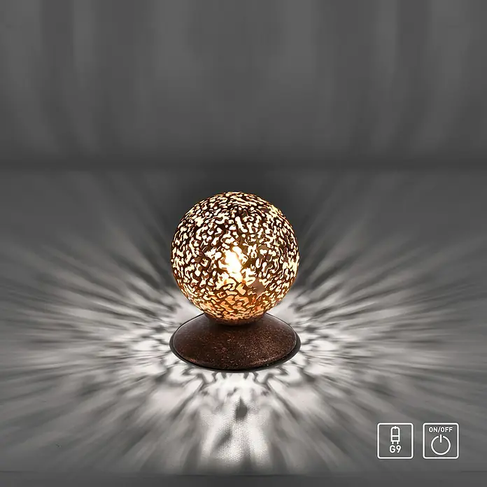 Paul Neuhaus Greta Lámpara de sobremesa redonda - 40 W, Ø x Al: 100 mm x 13 cm, Oro, G9 - Primer plano de una lámpara esférica decorativa con intrincados recortes, que proyecta un patrón de luz ambiental.