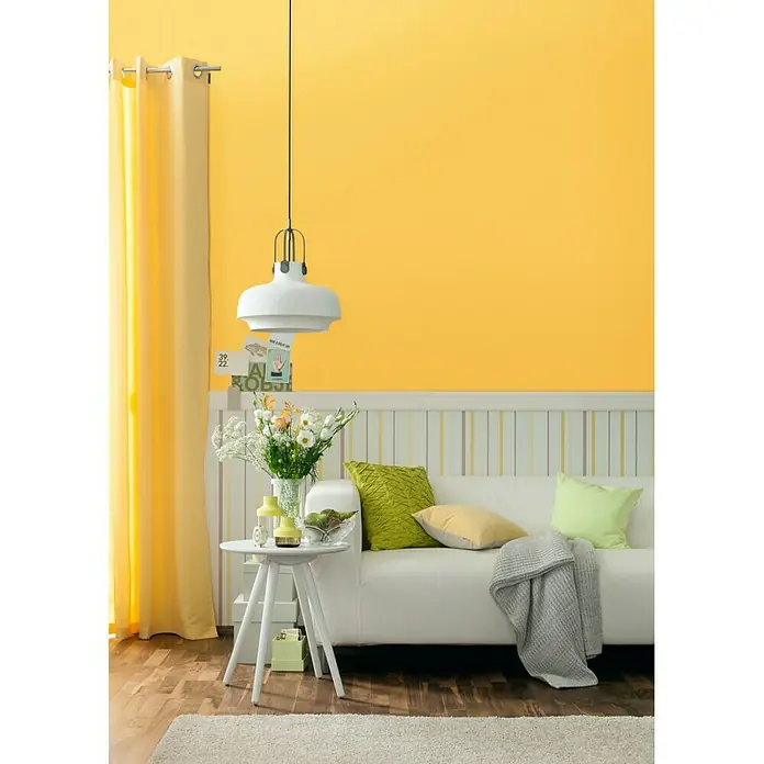 SCHÖNER WOHNEN-Farbe Wandfarbe Trendfarbe - Honey, Matt, 2,5 l, Konservierungsmittelfrei - Wohnzimmer mit gelber Wand und weißem Sofa, stilvoller Einrichtung und einer modernen Pendelleuchte für ein gemütliches Ambiente.