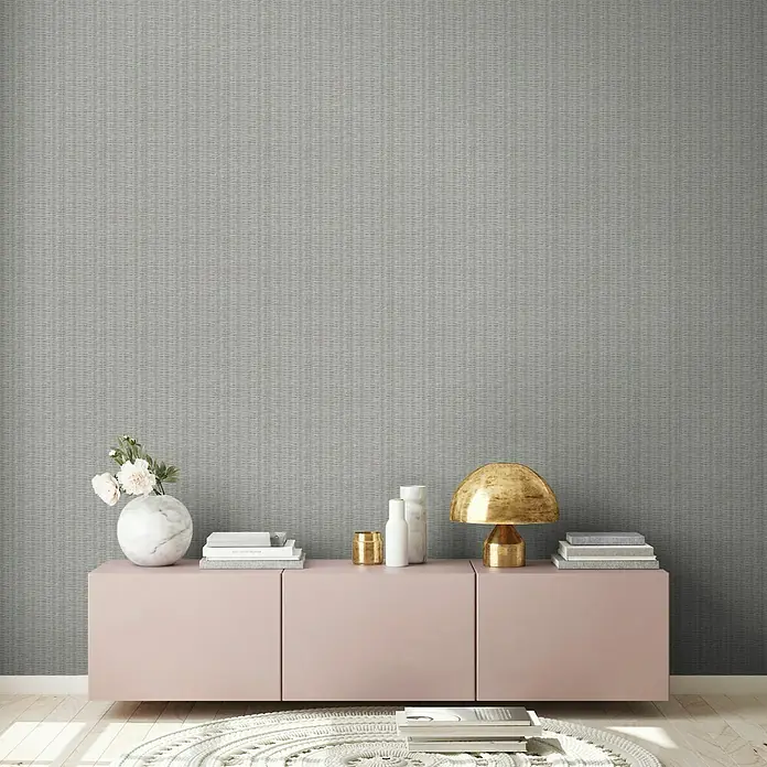 A.S. Création New Walls Vliestapete Rattan - Grau, Holzoptik, 10,05 x 0,53 m - Elegantes Zimmer mit rosafarbenem Sideboard, dekorativen Accessoires und einer stilvollen goldenen Lampe. Ideal für modernes Wohnen.