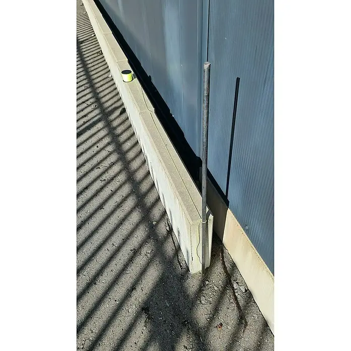 Heka Schnurstift - Länge: 120 cm, Durchmesser: 18 mm - Nahaufnahme einer grünen Schnurrolle und einer Metallstange an einer Betonmauer, die ein einfaches, aber funktionales Werkzeug-Setup zeigt.