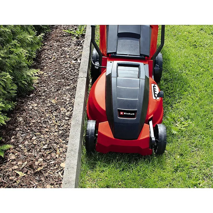 Einhell Elektro-Rasenmäher GC-EM 1742 - 1.700 W, Schnittbreite: 42 cm - Roter Einhell Rasenmäher steht auf einem Rasenstück neben einem Beet. Das Gerät ist kompakt und wirkt neuwertig.