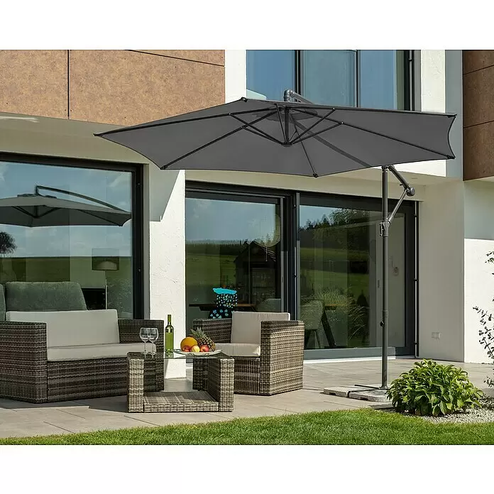 Schneider Classic Ampelschirm rund Venus - Anthrazit, Durchmesser Bespannung: 300 cm - Grauer Ampelschirm beschattet eine Rattan-Gartengarnitur mit Sofa, Sessel und Glastisch auf einer Terrasse am Haus.