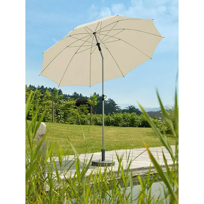 Schneider Classic Marktschirm rund Locarno - Natur, Durchmesser Bespannung: 220 cm - Ein cremefarbener Sonnenschirm steht auf einer Holzterrasse mit Blick auf einen Garten. Der Schirm bietet Schutz vor der Sonne.