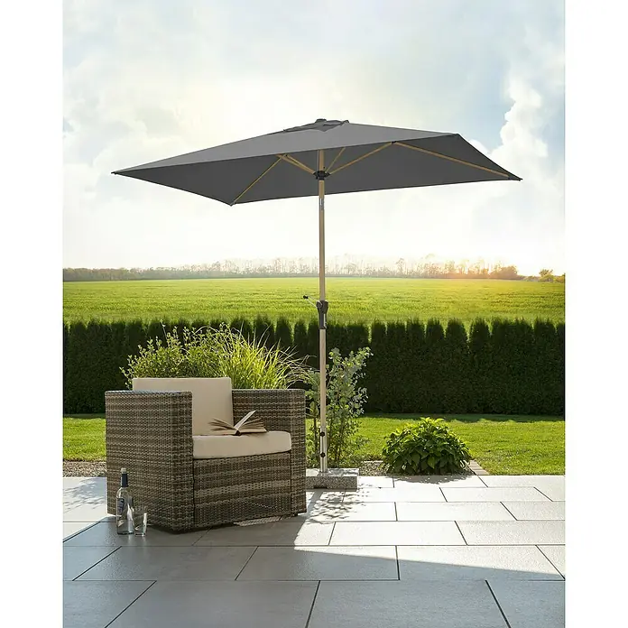 Schneider Classic Marktschirm Cordoba - Anthrazit, Bespannungsmaß (L x B): 230 x 150 cm - Ein grauer rechteckiger Sonnenschirm steht neben einem Korbsessel auf einer Terrasse, ideal für entspannte Stunden im Freien.