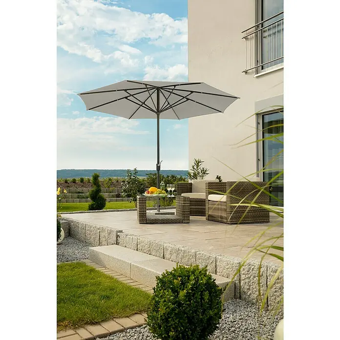 Schneider Classic Marktschirm rund Korsika - Silbergrau, Durchmesser Bespannung: 320 cm - Bild einer Gartenszene mit einem grauen Sonnenschirm, der eine Sitzecke mit Korbmöbeln und einem Tisch mit Obst und Wein beschattet.