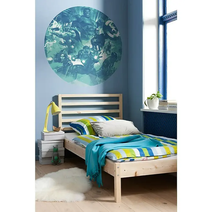 Komar Dots Fototapete rund Avengers Blue Power - 125 cm, Selbstklebend - Kinderzimmer mit rundem Avengers-Wandaufkleber über einem hellen Holzbett mit gestreifter Bettwäsche in Blau, Grün und Gelb.