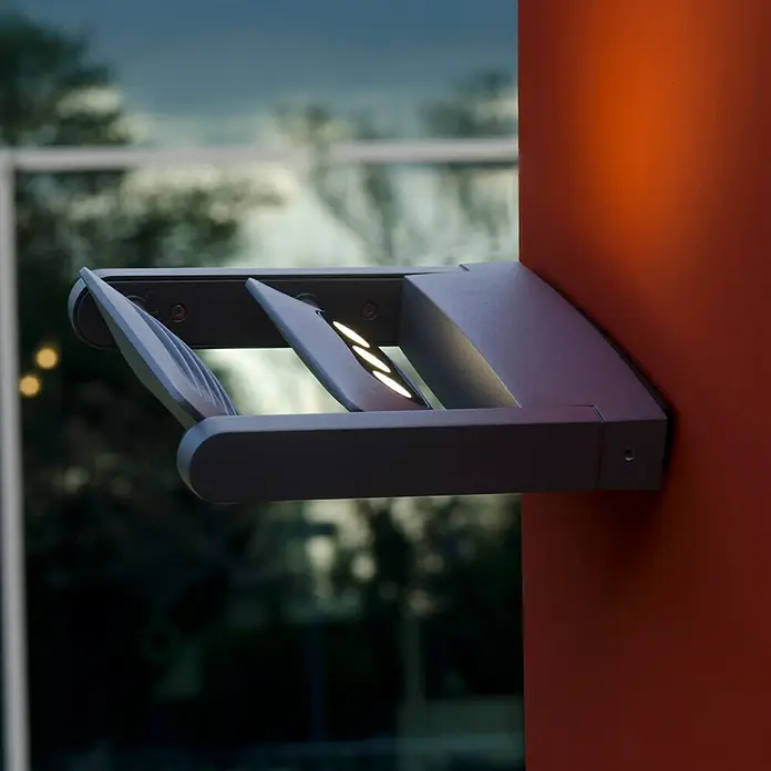 Lutec Aplique para exterior LED - Color del marco: Antracita, IP65, 18 W, Número de bombillas: 2 ud. - Lámpara de pared moderna en gris con tres puntos de luz, montada en una pared naranja.