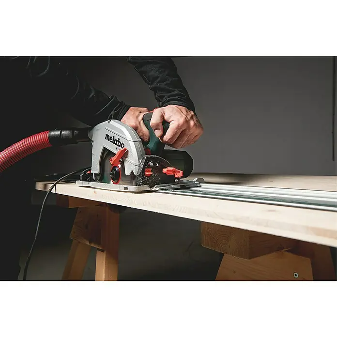 Metabo Handkreissäge KS 66FS1.500 W, Durchmesser Sägeblatt: 190 mm, Schnitttiefe bei 90 °: 66 mm - Eine Metabo KS 66 Handkreissäge mit Absaugung wird auf einer Holzarbeitsfläche mit Führungsschiene verwendet, um präzise Schnitte zu erzielen.