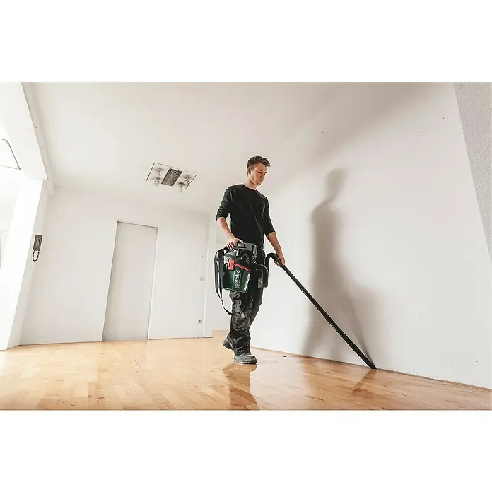 Metabo CAS 18V Akku-Nass-Trockensauger AS 18 L PC Compact - 18 V, Ohne Akku, Behältervolumen: 6 l - Ein Mann saugt mit einem Metabo Akku-Sauger einen Holzboden. Der Sauger ist grün, schwarz und rot.