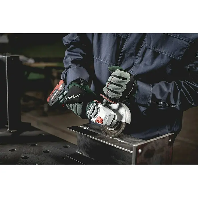 Metabo CAS 18V Akku-Winkelschleifer W 18 LT BL 11-125 - 2 Akkus, 4 Ah, Durchmesser Scheibe: 125 mm - Nahaufnahme eines Metabo Winkelschleifers in Aktion, bedient von einer Person in Arbeitskleidung. Der Schleifer bearbeitet ein Metallstück.