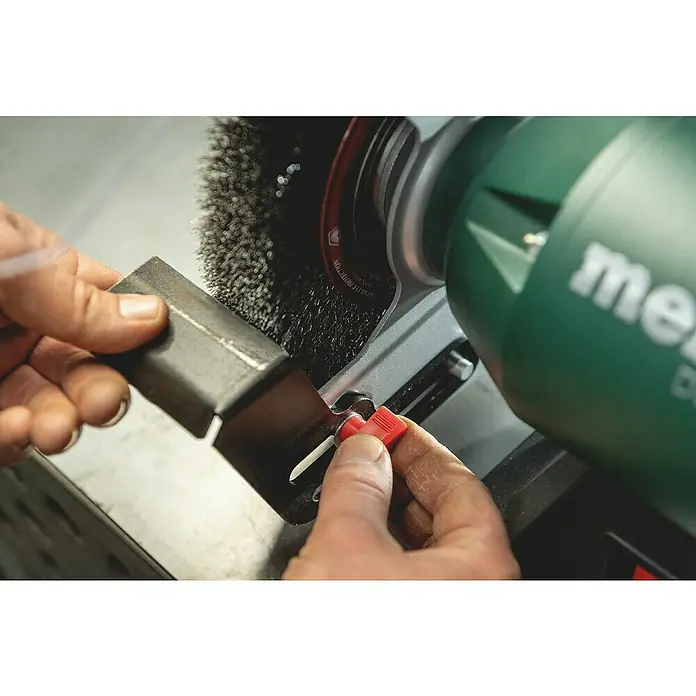 Metabo Band- & Tellerschleifer BS 200 Plus - 600 W, 2.980 U/min - Nahaufnahme einer Metabo-Doppelschleifmaschine beim Bearbeiten eines Metallstücks mit einer Drahtbürste. Präzision und Leistung vereint.