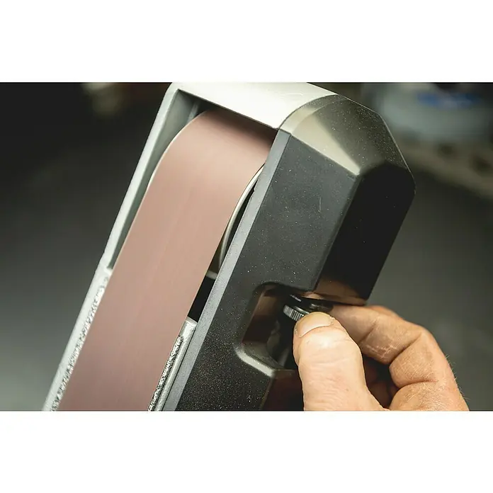 Metabo Band- & Tellerschleifer BS 200 Plus - 600 W, 2.980 U/min - Detailaufnahme eines Bandschleifers beim Justieren, der braune Schleifband und einen verstellbaren Knopf zeigt.