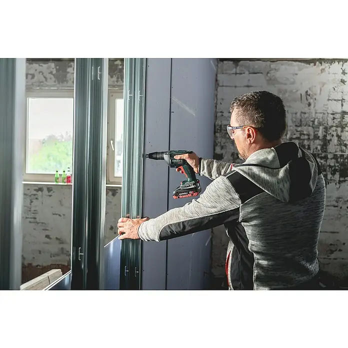 Metabo CAS 18V Akku-Trockenbauschrauber TBS 18 LTX BL 5000 - 18 V, 2 Akkus, 2 Ah - Ein Mann befestigt eine Wand mit einem Metabo Schrauber, ideal für Trockenbauarbeiten.