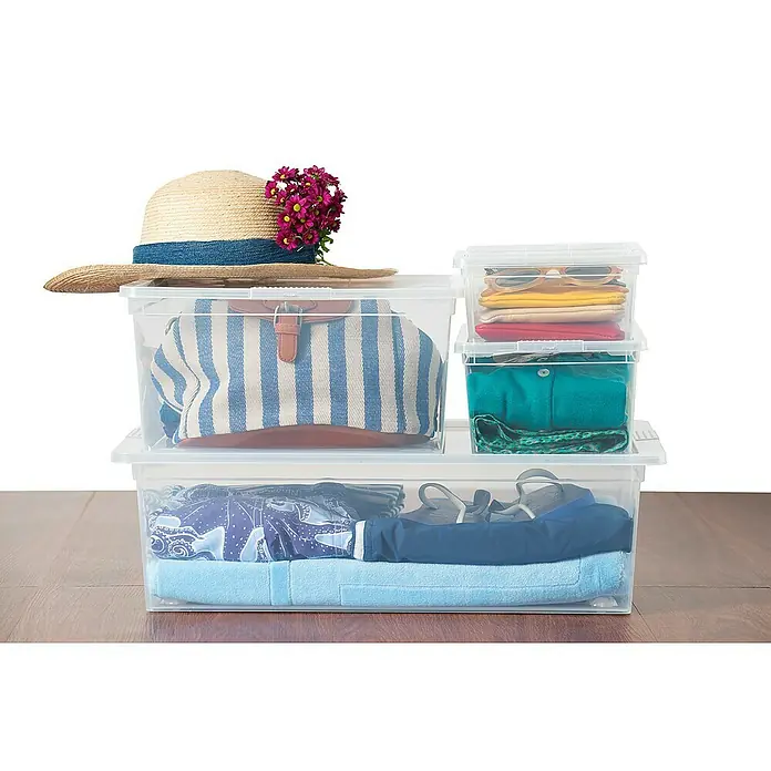 KIS Aufbewahrungsbox C-Box M+ - 34 x 40 x 17 cm, 18 l, Transparent - Die durchsichtigen Aufbewahrungsboxen aus Kunststoff präsentieren Kleidung, Accessoires und einen Hut mit floralem Akzent auf einem Holztisch.