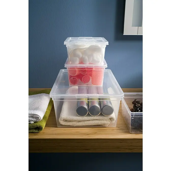 KIS Aufbewahrungsbox C-Box XXS+ - 16,5 x 19,5 x 9,5 cm, 2 l, Transparent - Aufnahme von transparenten Aufbewahrungsboxen mit Badartikeln auf einer Holzoberfläche vor einer blauen Wand.