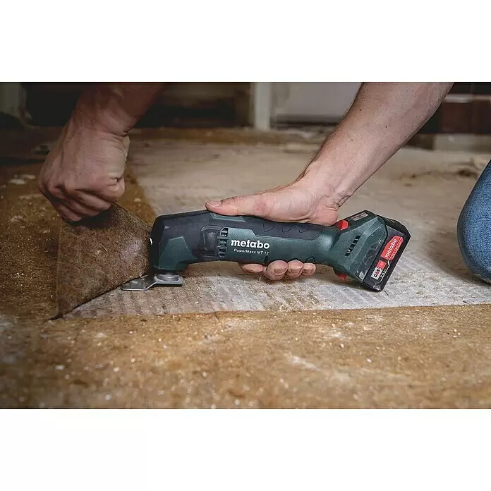 Metabo Akku-Multifunktionswerkzeug POWERMAXX MT 12 - 12 V, Ohne Akku - Mann nutzt grünes Metabo PowerMaxx MT 12 Akku-Multifunktionswerkzeug zum Entfernen von braunem Bodenbelag.