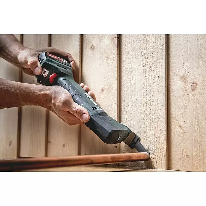 Metabo Akku-Multifunktionswerkzeug POWERMAXX MT 12 - 12 V, Ohne Akku - Hände verwenden ein grünes Metabo Multifunktionswerkzeug, um Holz für eine Kupferrohrinstallation zu schneiden.