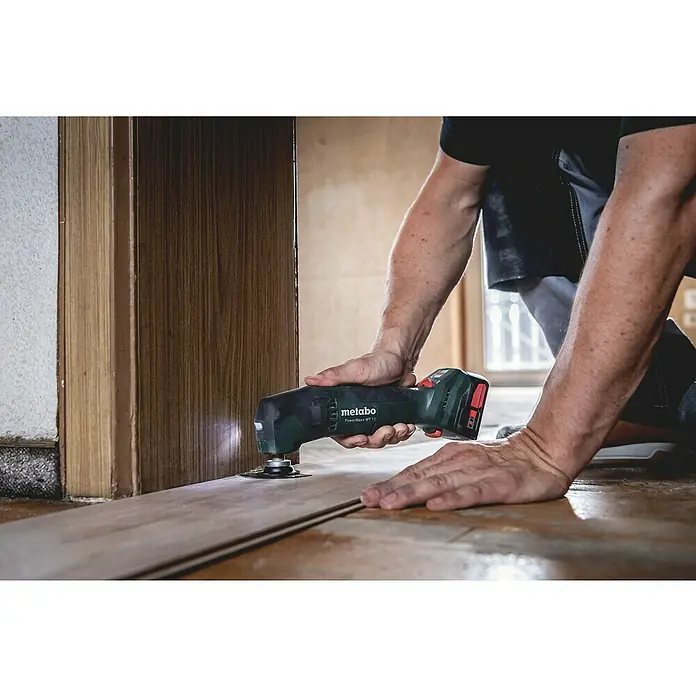 Metabo Akku-Multifunktionswerkzeug POWERMAXX MT 12 - 12 V, Ohne Akku - Ein Mann benutzt eine Metabo PowerMaxx MT 12 Multifunktionswerkzeug, um Laminatboden an einer Tür zu bearbeiten.