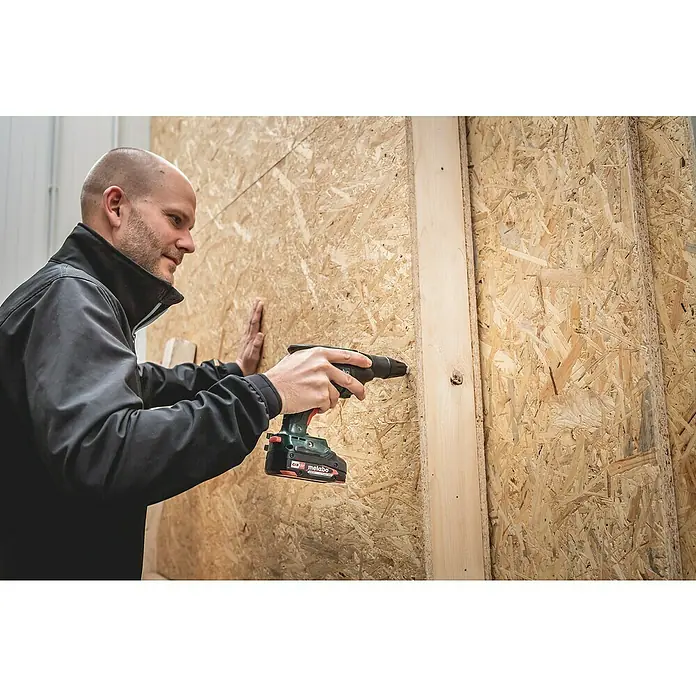 Metabo CAS 18V Akku-Trockenbauschrauber HBS 18 LTX BL 3000 - 18 V, 2 Akkus, 2 Ah - Ein Handwerker befestigt eine Holzlatte mit einem Metabo Akku-Bohrschrauber an einer OSB-Platte. Das Werkzeug ist gut sichtbar.