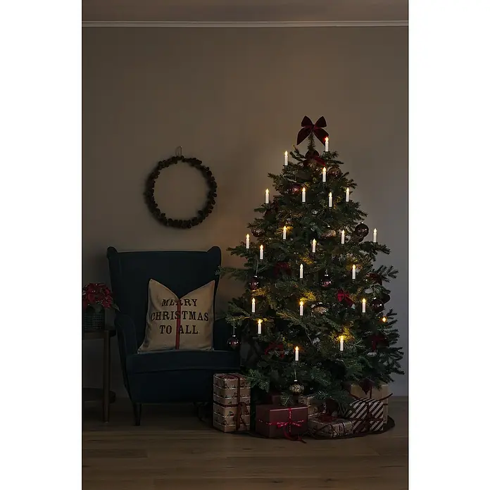 Konstsmide LED-Weihnachtskerzen - 15,5 m, Weiß, Lichtfarbe: Bernstein, Anzahl Leuchtmittel: 16 Stk., IP20 - Festlich geschmückter Weihnachtsbaum mit Kerzen und Geschenken im gemütlichen Wohnzimmer.
