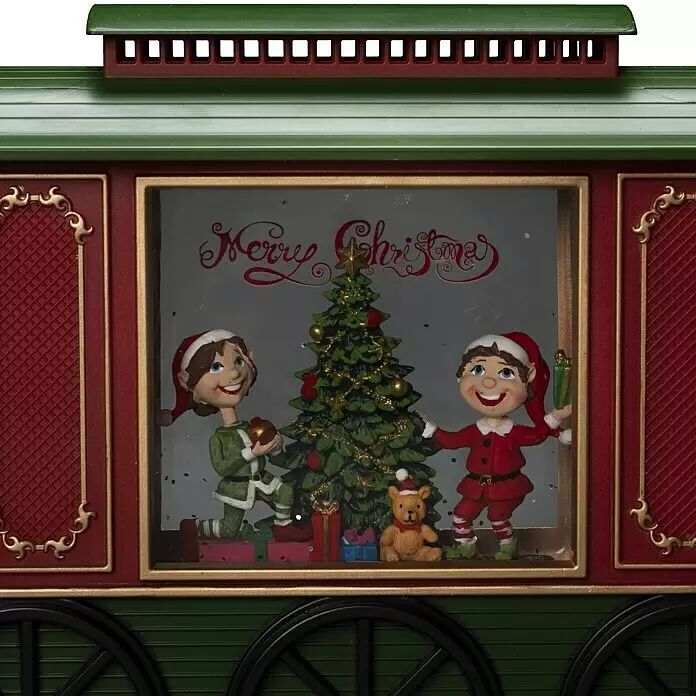 Konstsmide LED-Schneelaterne Wagon - Innen, Mehrfarbig, 24 x 9 x 19,5 cm, Wagon mit Christbaum, Batteriebetrieben - Ein festlicher grün-roter Weihnachtszugwagen mit Fenster, das zwei Elfen, einen geschmückten Weihnachtsbaum und 'Merry Christmas' zeigt.