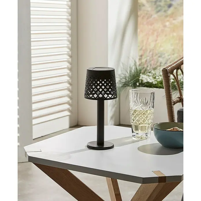 Luxform Manacor Lámpara de sobremesa solar - Negro, Ø x Al: 9 x 22 cm - Primer plano de una lámpara de mesa inalámbrica con panel solar en una mesa hexagonal.