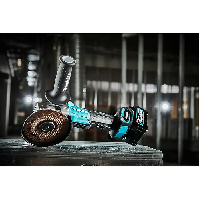 Makita XGT 40V max. Akku-Winkelschleifer GA013GZ - Ohne Akku, Leerlaufdrehzahl: 8.500 U/min - Nahaufnahme eines Akku-Winkelschleifers von Makita mit Griff und Akku, der auf einer Werkbank in einer Bauumgebung steht.