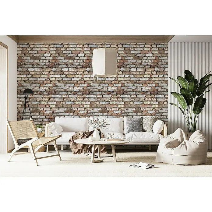 Papel pintado de vinilo Rústico - 280 x 90 cm, Marrón, Autoadhesivo - Un salón luminoso con un sofá blanco, un sillón y un puf, acentuado por una llamativa pared de ladrillo.