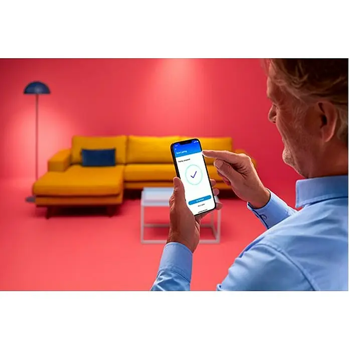 Philips Wiz LED-Deckenleuchte rund - 21 W, Ø x H: 40 x 4,5 cm, Schwarz, Kaltweiß - Mann interagiert mit einer Smart-Home-App auf seinem Smartphone. Der Bildschirm zeigt ein Häkchen, das eine erfolgreiche Aktion bestätigt.