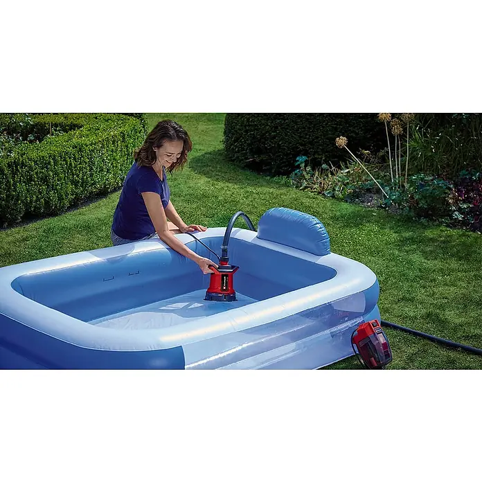 Einhell Power X-Change 18V Schmutzwasserpumpe GE-DP 18/25 LL Li-Solo - 160 W, 18 V, Max. Fördermenge: 7.000 l/h, Eintauchtiefe: 4 m - Frau benutzt eine rote Einhell Schmutzwasserpumpe zum Entleeren eines blauen Planschbeckens im Garten.