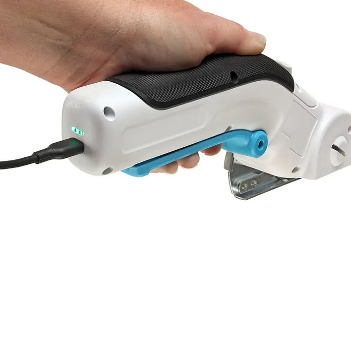 Black+Decker Cúter circular BCRC115-XJ - 3,6 V, 1,5 Ah, Iones de litio - Primer plano de un cortador rodante inalámbrico con cuerpo blanco, mango negro y detalles azules sostenido en una mano y cargándose.