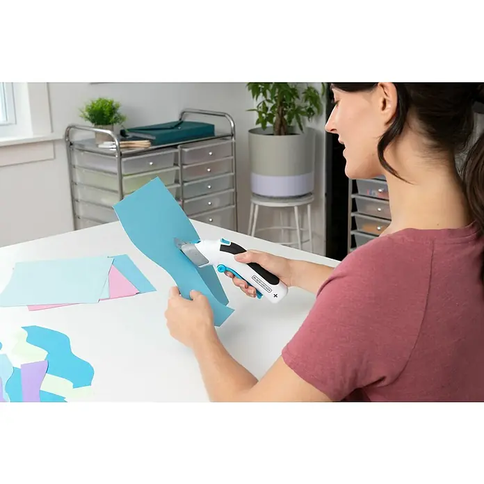 Black+Decker Grapadora de batería BCN115-XJ-Li - 3,6 V, 1 batería, 1,5 Ah - Mujer corta papel de colores con tijeras eléctricas BLACK+DECKER sobre una mesa. Ideal para manualidades y proyectos.